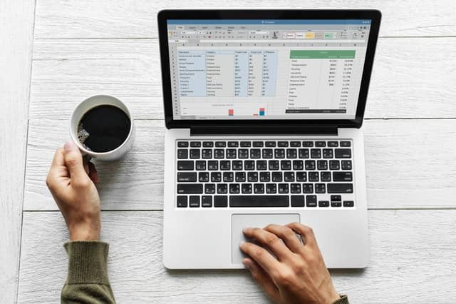 person typing on laptop with a cup of coffee