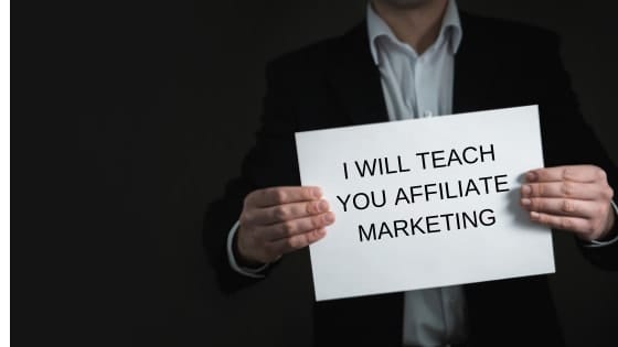 man holding sign that saysi will teach you affiliate marketing